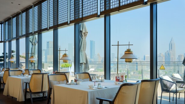 A restaurant with tables set for dining, large windows offering a city view, and hanging pendant lights. - UrCove by Hyatt Nanjing Confucius Temple (Nanjing)