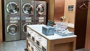 A hotel laundry room with multiple washing machines, a counter with laundry bags, and a wooden wall. - UrCove by Hyatt Nanjing Confucius Temple (Nanjing)