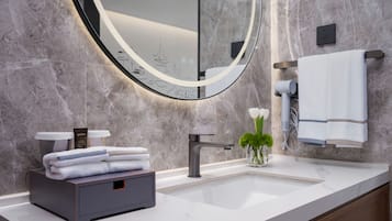 Un baño moderno con pared de mármol, un espejo redondo, un lavabo y un perchero para toallas.