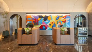 A lobby with two reception desks, a colorful abstract mural, and a marble floor. - UrCove by Hyatt Nanjing Confucius Temple (Nanjing)