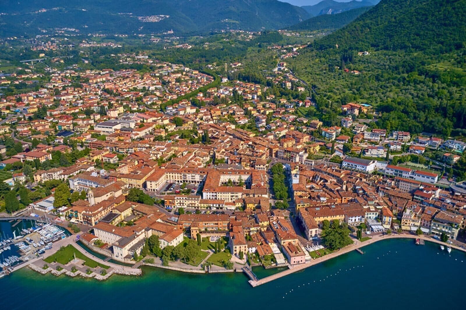 An aerial view of a coastal town with dense housing, a marina, and a prominent waterfront area.