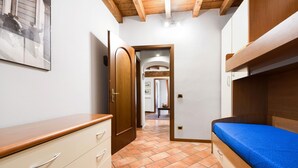 A narrow hallway with a wooden bench, a wardrobe, and a door leading to another room.