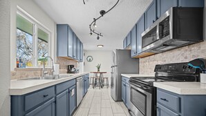 Une cuisine moderne avec des armoires bleues, une cuisinière en acier inoxydable et un four à micro-ondes.