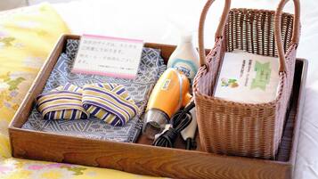A wooden tray with a woven basket, a hairdryer, a bottle of lotion, and a folded towel.