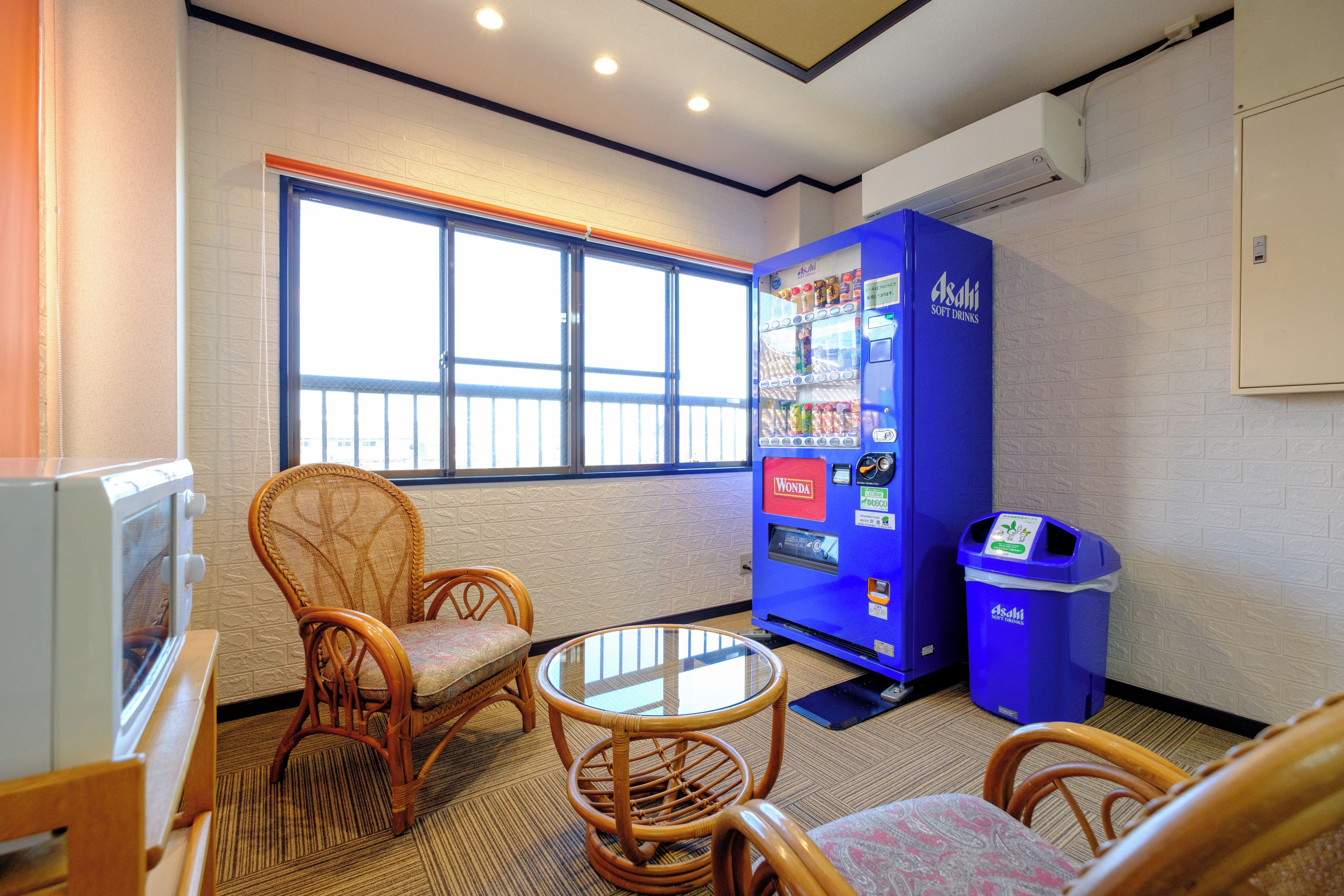 A room with a seating area, a vending machine, and a window.