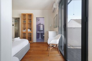 A bedroom with a bed, a wooden wardrobe, a bathroom with a sink and mirror, and a balcony with a view. - Delightful Family Flat with Terrace (Milan)