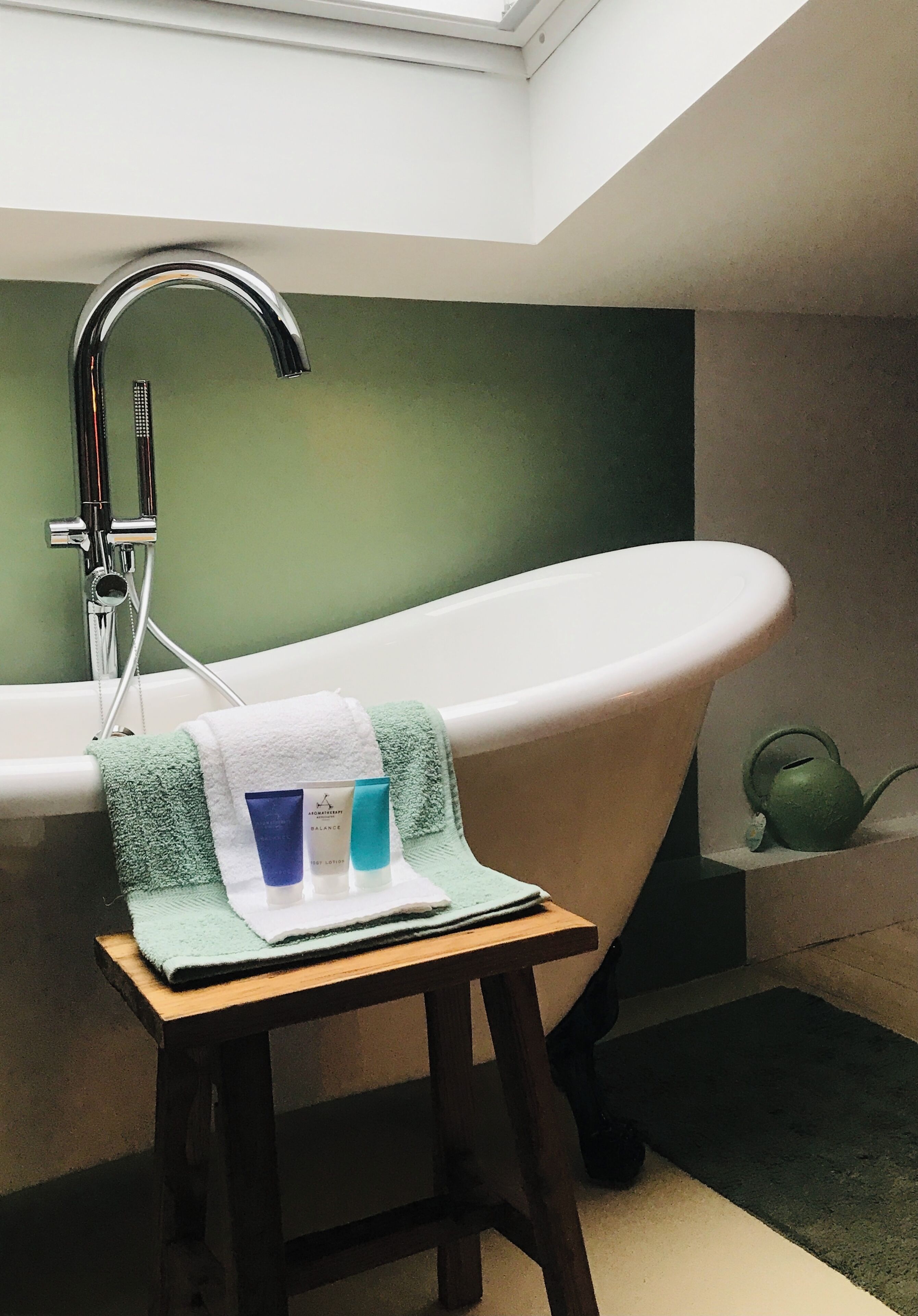 Ein Badezimmer mit freistehender Badewanne, einem Handtuchhalter und einem kleinen Hocker mit Toilettenartikeln.