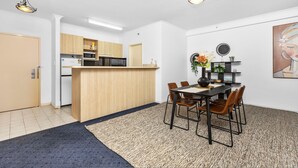Une cuisine compacte dotée de meubles en bois, d’un îlot central et d’un coin repas avec une table et des chaises.