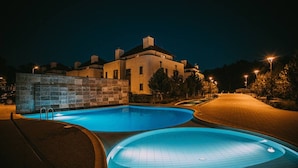 A swimming pool area at night with a stone wall and a building in the background. - Violino 6 Os b Nowoczesny 5 min do Pla y (Trzebiatow)