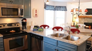 A kitchen with stainless steel appliances, a granite countertop, and a dining area with red chairs.