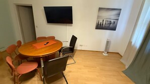 A conference room with a round table, six chairs, a TV, and a painting on the wall.