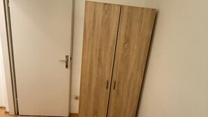 A room with a wooden wardrobe and a closed door.