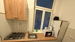 A compact kitchen with a gas stove, a sink, a microwave, and wooden cabinets.