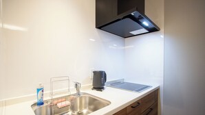 Een moderne keuken met een roestvrijstalen spoelbak, houten kastjes, een waterkoker en een waterkokermat.