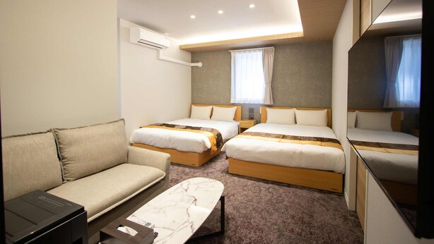 Een hotelkamer met twee bedden, een slaapbank, een bureau en een grote spiegel.