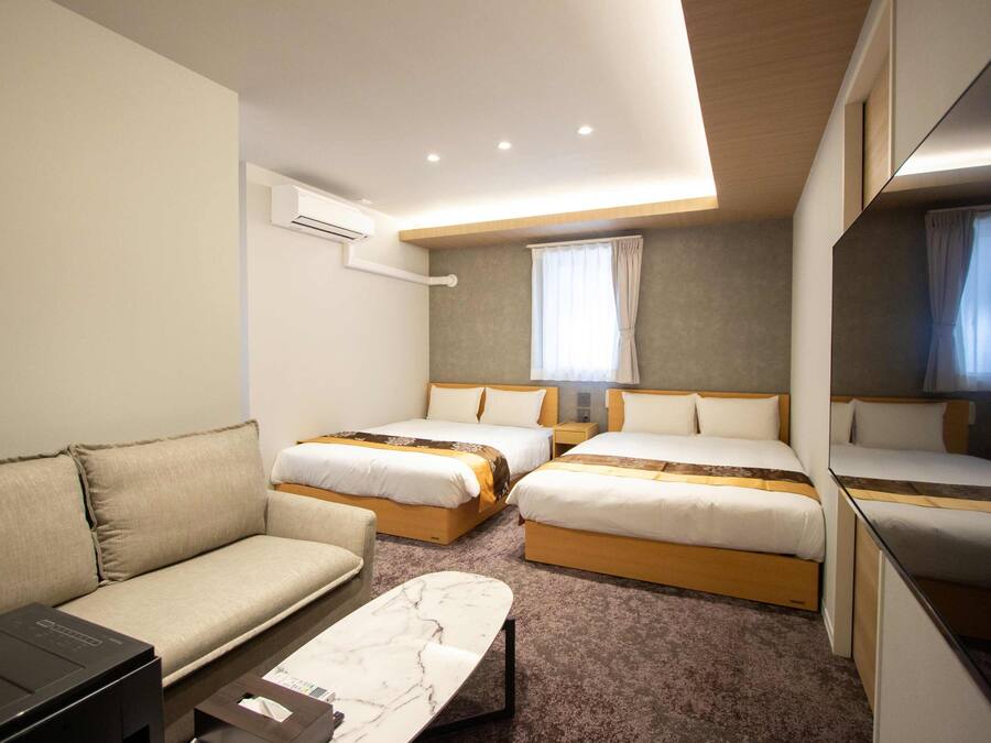 Una habitación de hotel con dos camas, un sofá, un escritorio y un espejo grande.