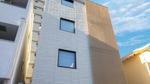 Een modern meerhoogbouw gebouw met een platte gevel, grote ramen en een zichtbare garage-ingang.