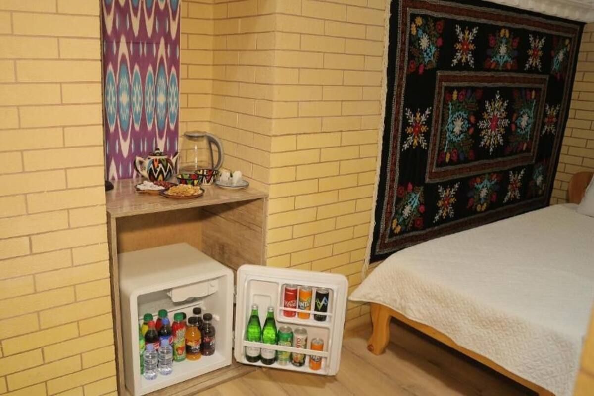 Quarto de hotel com uma cama, um frigorífico com bebidas e um papel de parede estampado.