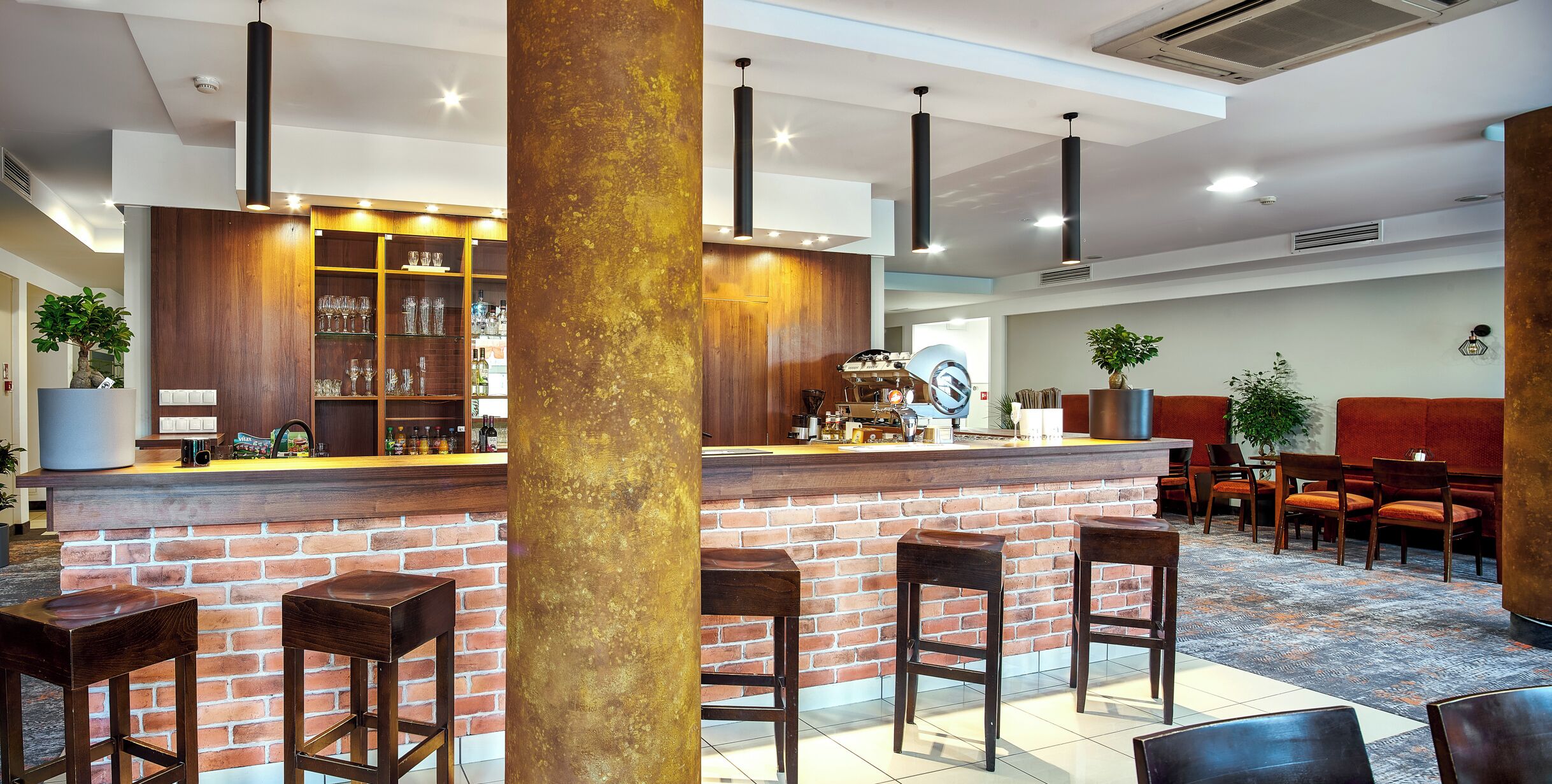 A bar area with a brick counter, wooden stools, and a seating area with chairs and a table.
