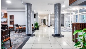 A modern hotel lobby with a central corridor, marble pillars, and a mix of seating areas. - Hotel Anton (Pruszków)