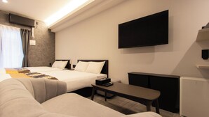 Una habitación de hotel con dos camas, un televisor de pantalla plana, un escritorio y un refrigerador pequeño.