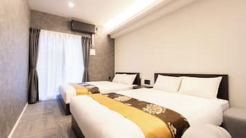 A hotel room with two beds, a large window with curtains, a flat-screen TV mounted on the wall, and a carpeted floor.
