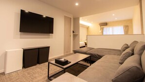 Una sala de estar moderna con una televisión de pantalla plana, un sofá, una mesa de centro y una mesita auxiliar.