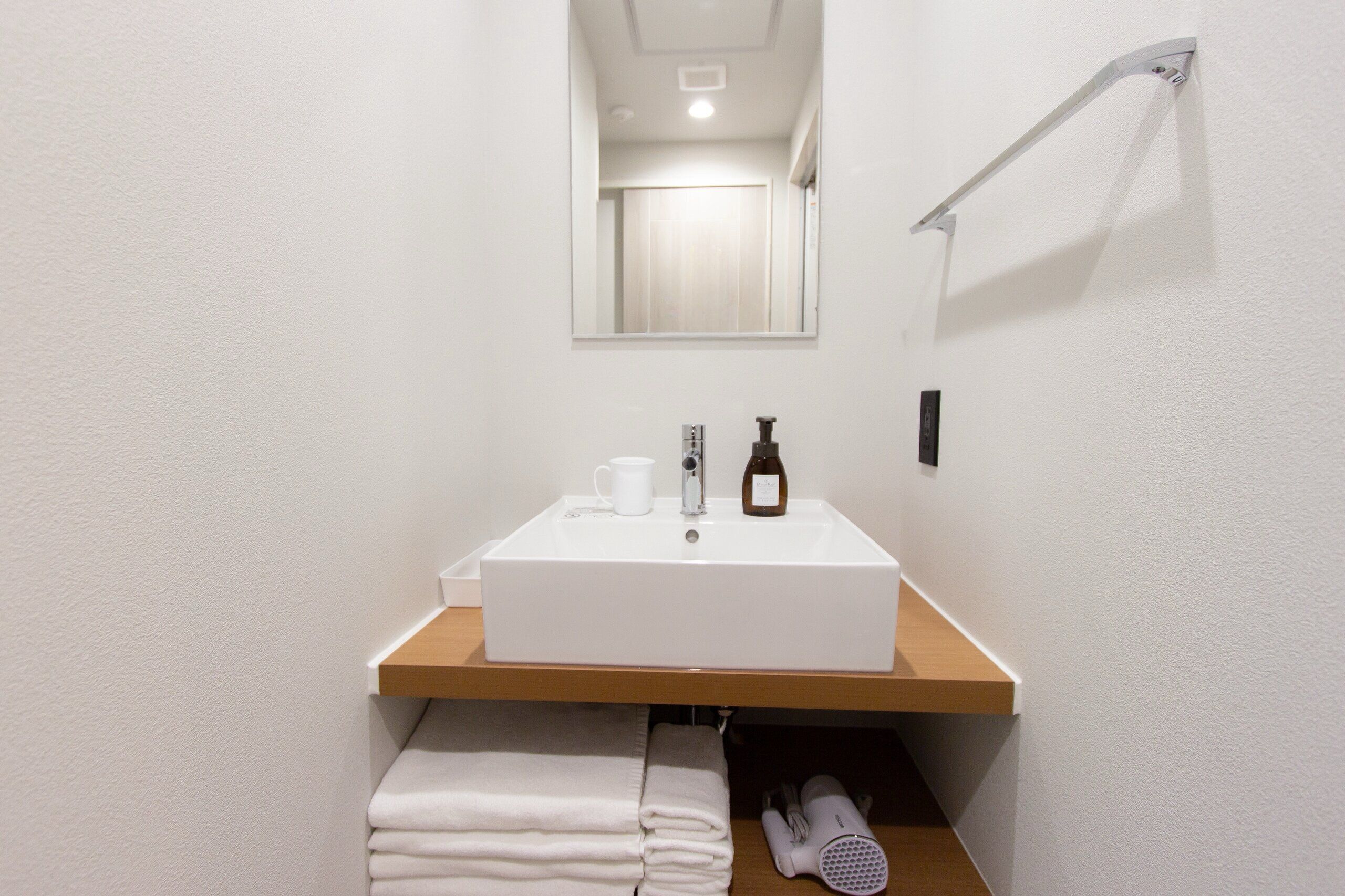 A modern bathroom with a white sink, a mirror, and a towel rack.