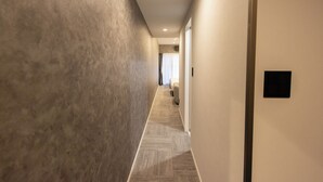 Un pasillo con pared texturizada, suelo alfombrado y una puerta con panel negro.