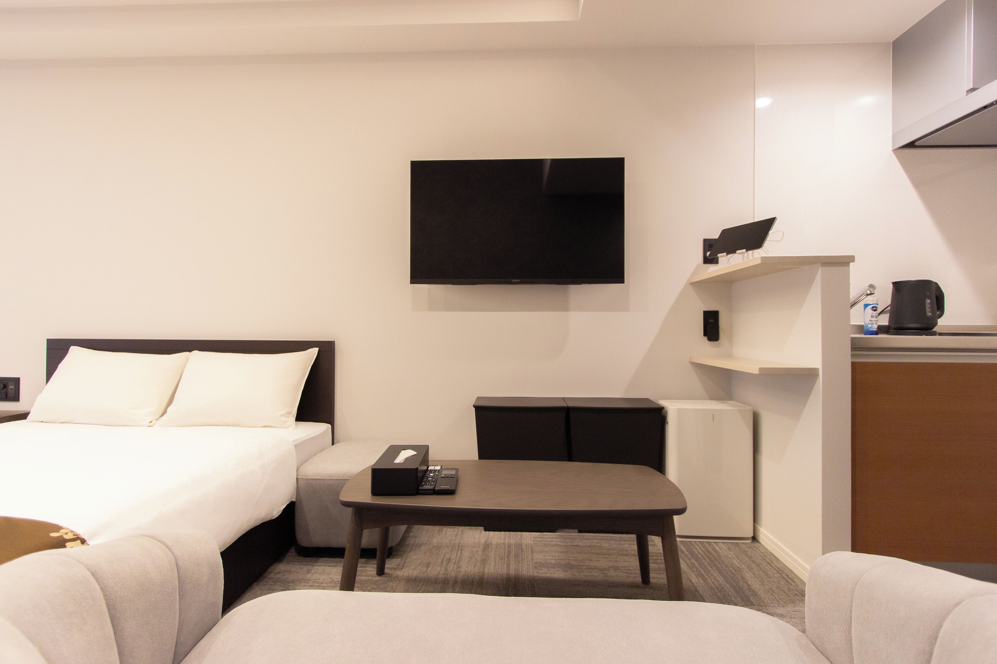 Hotellihuone, jossa on sänky, työpöytä, televisio ja kahvinkeitin.