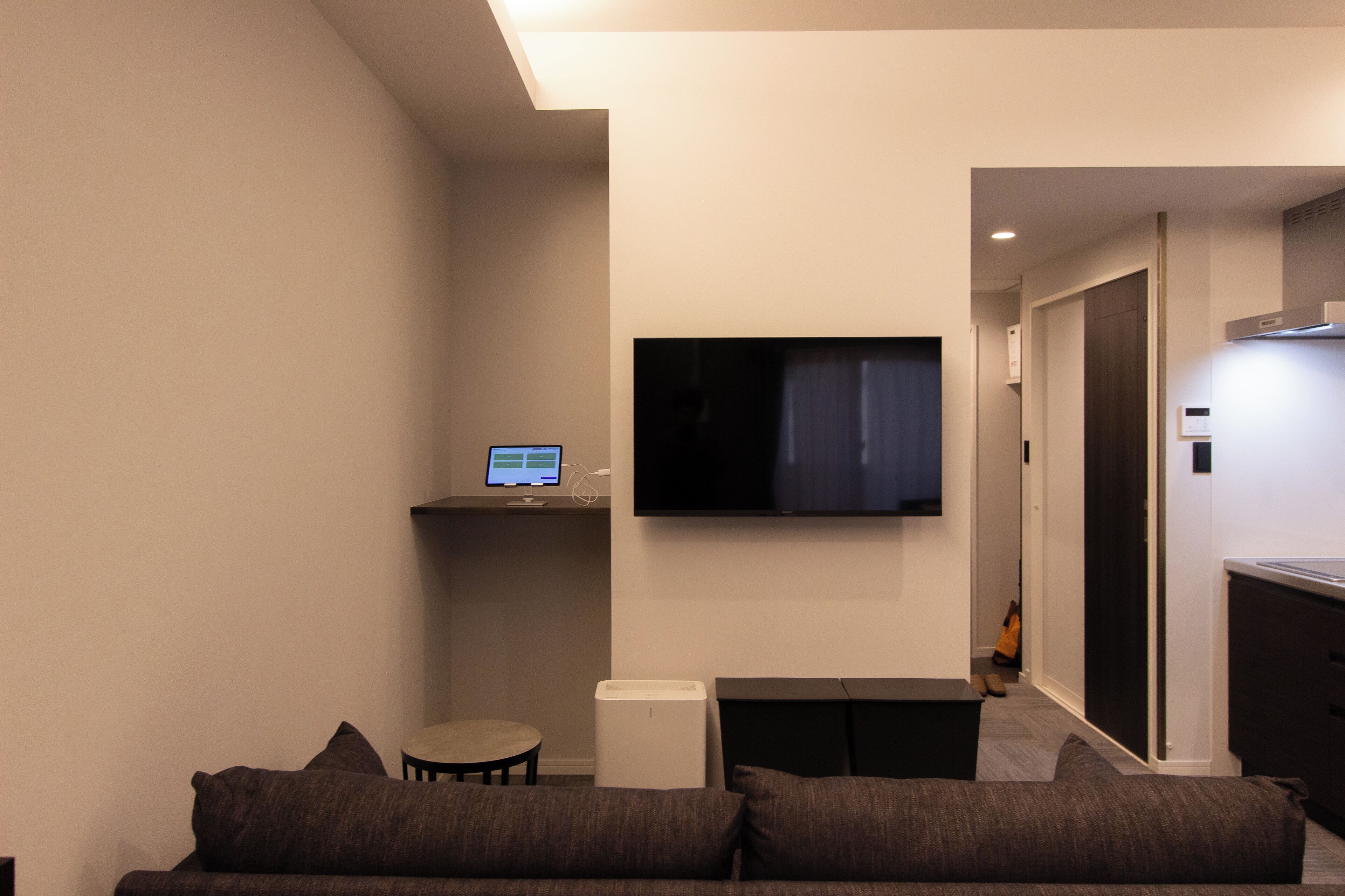 Un salon moderne avec un téléviseur à écran plat fixé au mur, une petite table ronde et un canapé agrémenté de coussins.