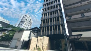 Un edificio moderno de varios pisos con un diseño vertical destacado, que presenta una serie de balcones y amplias ventanas.