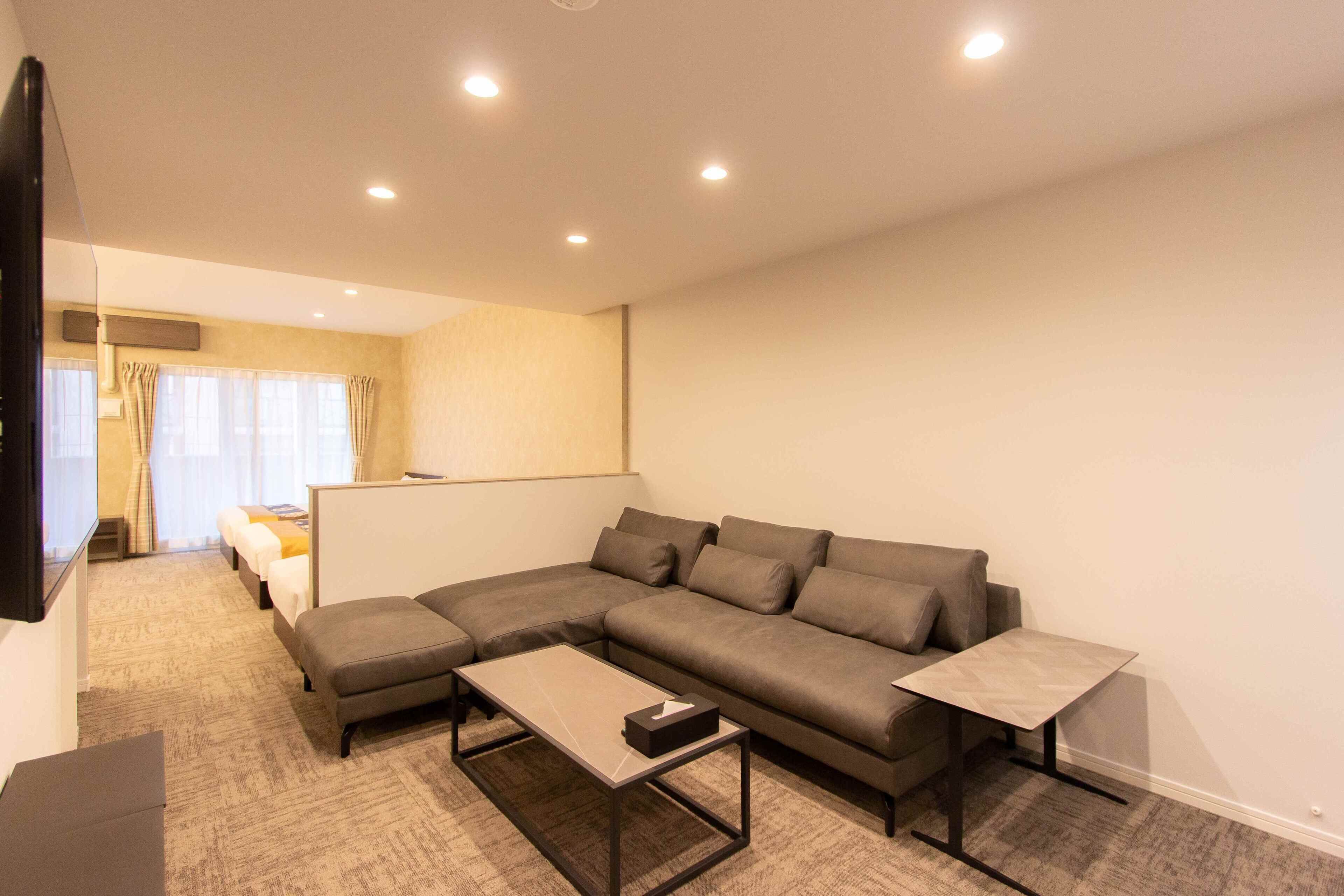 A modern living room with a sectional sofa, a coffee table, and a TV mounted on the wall.