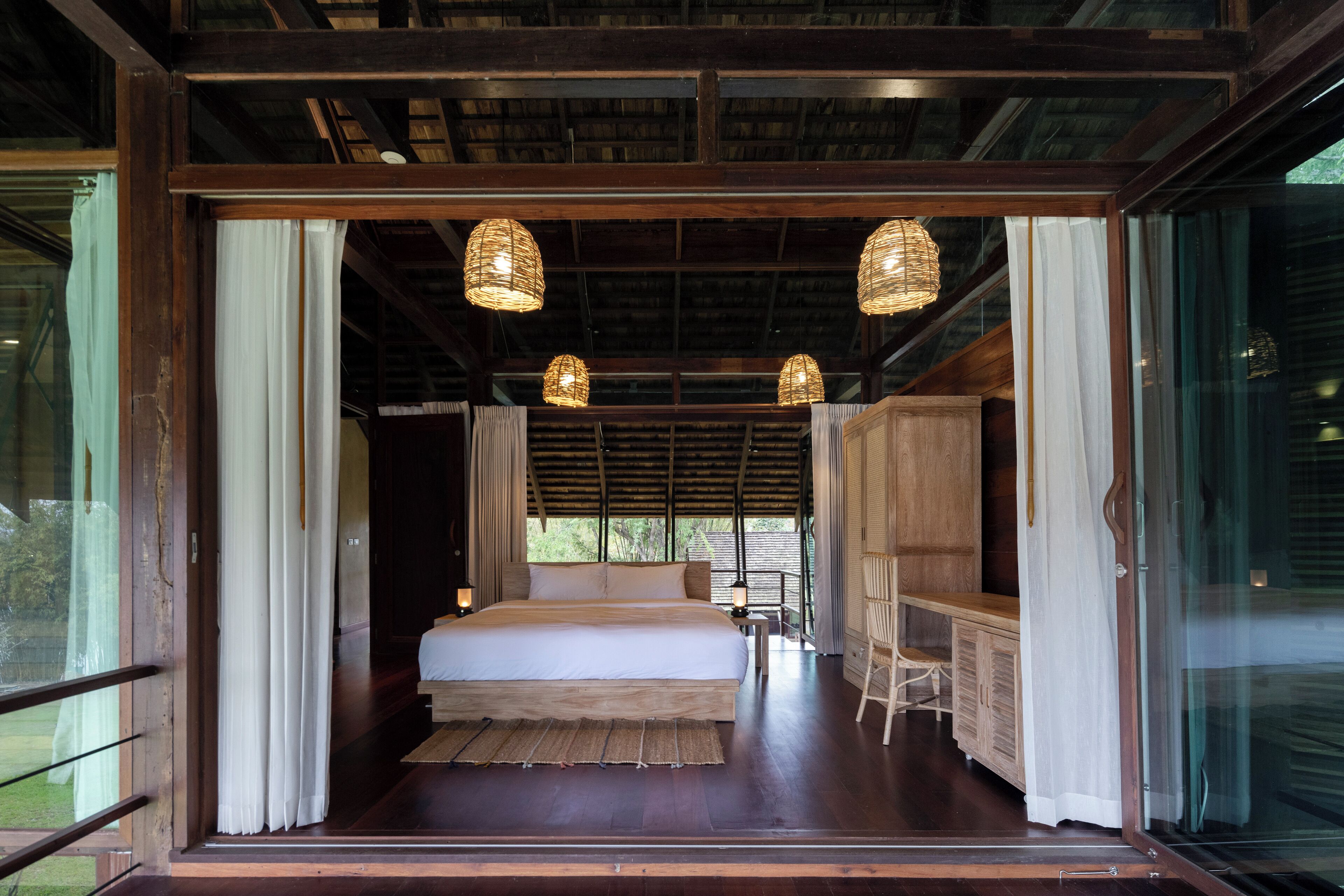 A spacious bedroom with a large bed, wooden furniture, and hanging light fixtures.