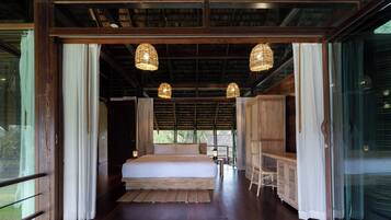 A spacious bedroom with a large bed, wooden furniture, and hanging light fixtures.
