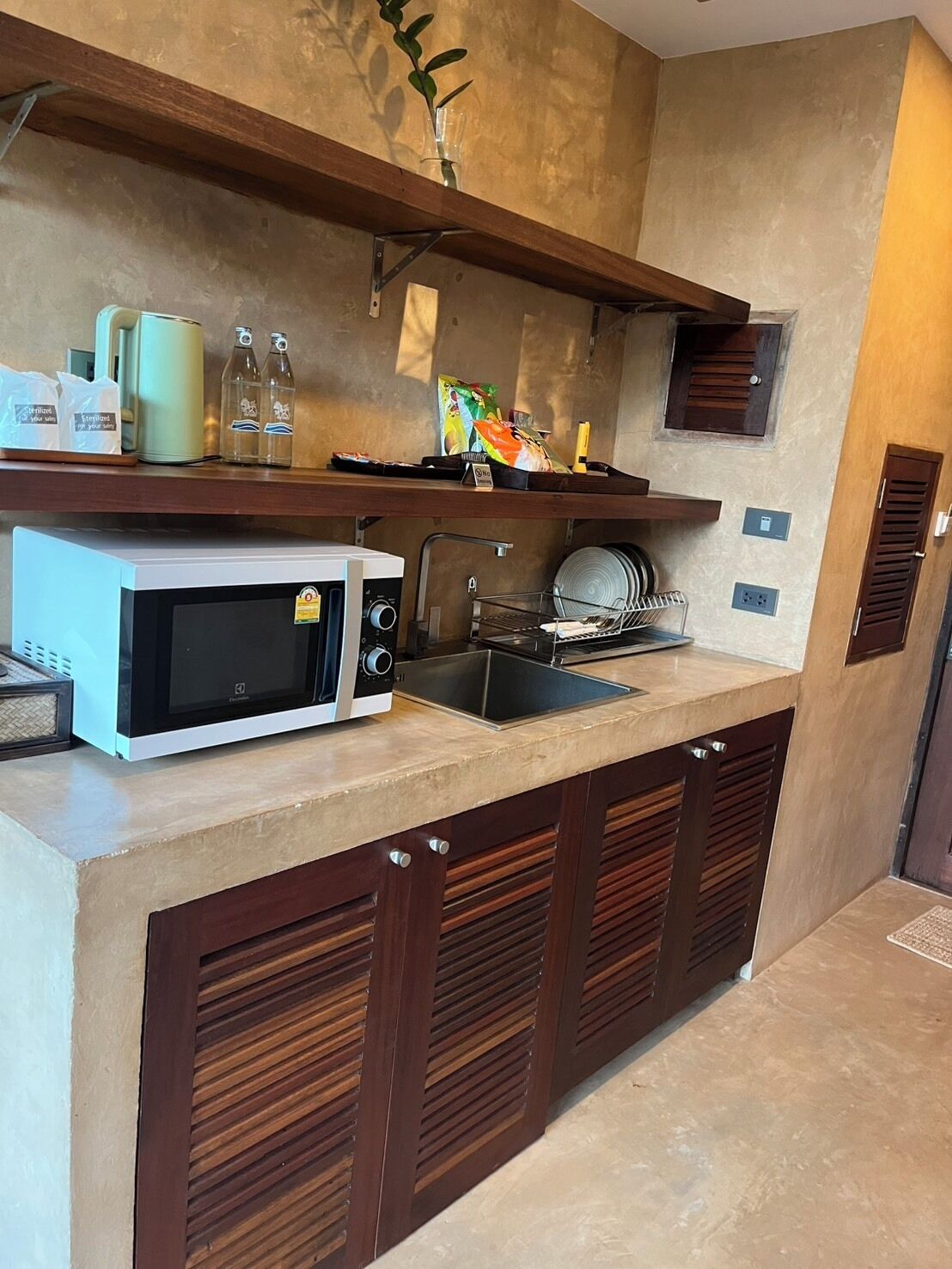 A compact kitchen with a microwave, sink, and wooden cabinets.