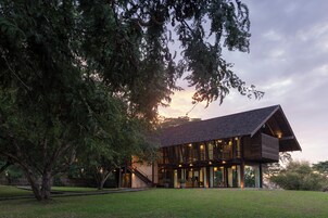 Una casa moderna con un amplio frente de cristal, revestimiento de madera y un jardín delantero espacioso.