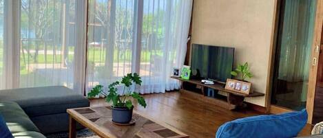 A spacious living room with a large window, a sofa, a coffee table, and a television.