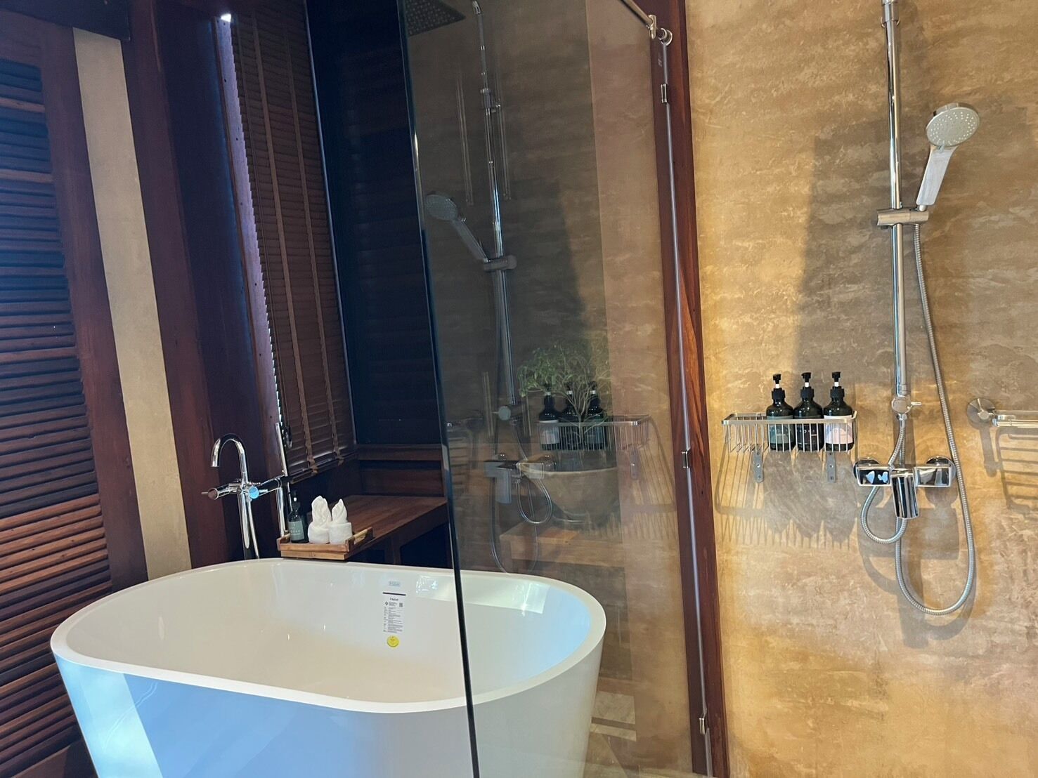 A modern bathroom with a freestanding bathtub, a glass-enclosed shower area, and a wooden vanity with a mirror.