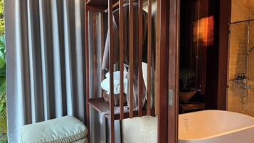A bathroom with a freestanding bathtub, wooden paneling, and a towel rack.