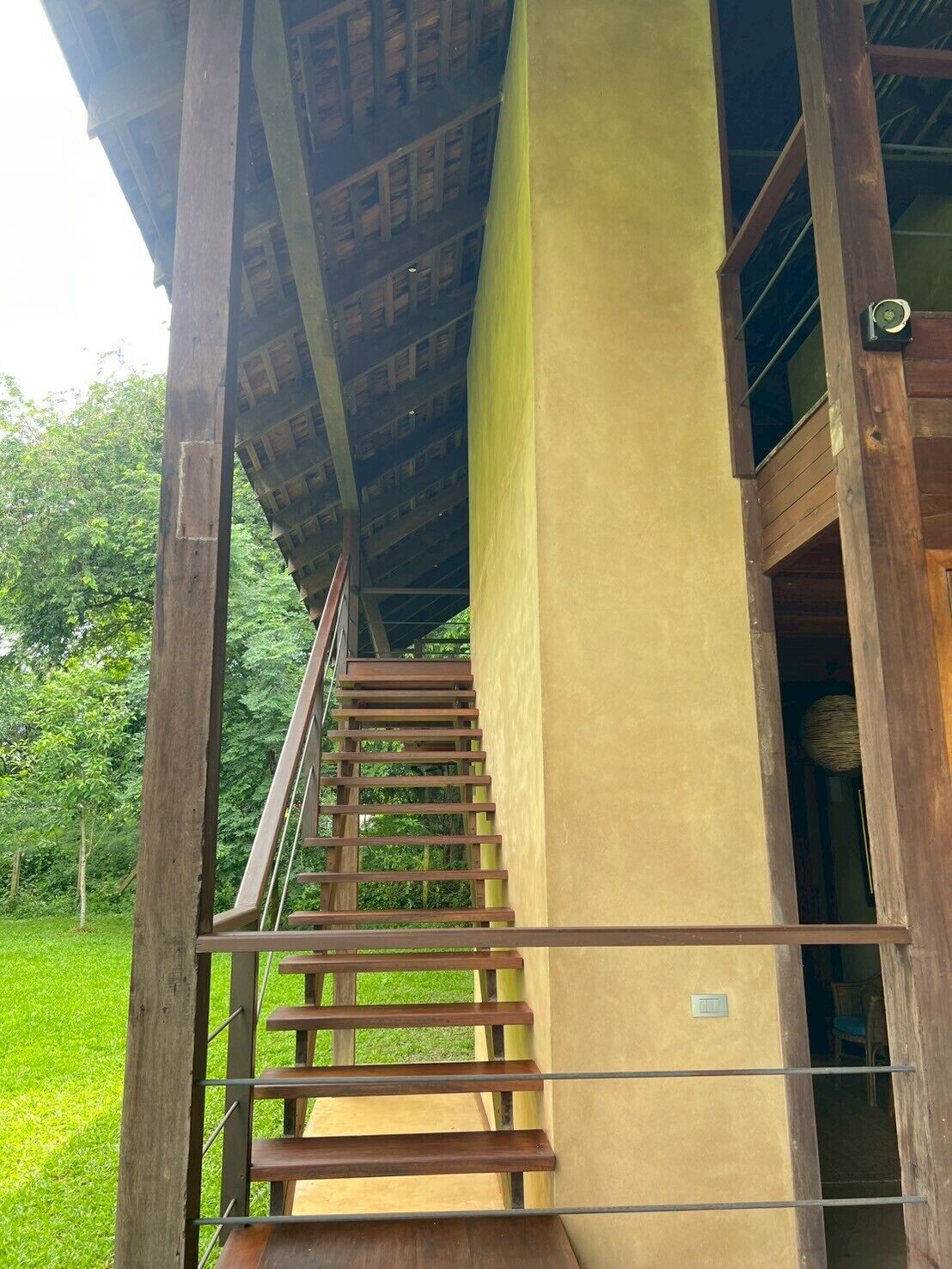 A wooden staircase leading to an upper level with a yellow wall and a window.