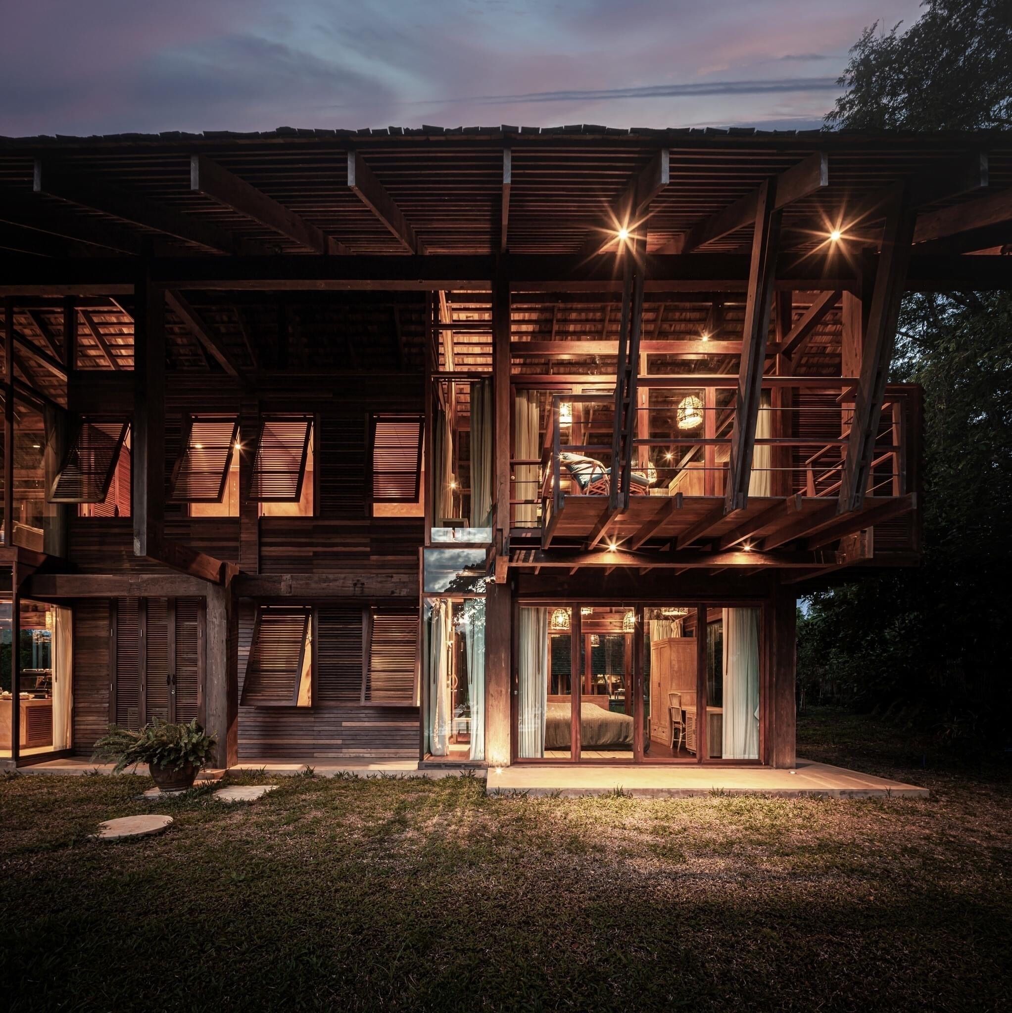 A modern wooden house with multiple levels, large windows, and a well-lit interior.