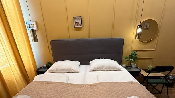 Ett hotellrum med en stor säng, en sänggavel, ett nattduksbord, en stol, ett bord och en spegel.