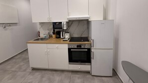 Ett kompakt kök med vita skåp, en ugn från Bosch, ett kylskåp från Bosch, en mikrovågsugn, en brödrost och ett handfat.