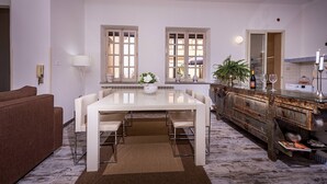 Un comedor con una mesa y sillas blancas, un sofá marrón y una cocina con un armario rústico.