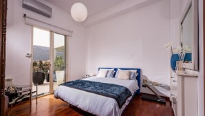 Un dormitorio con cama, mesita de noche, espejo y vistas al exterior.