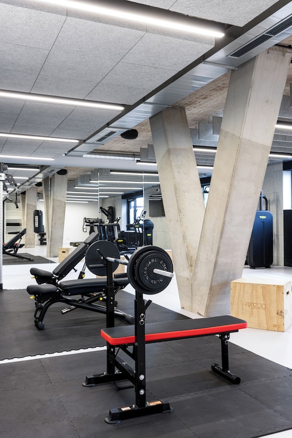 A gym with weightlifting equipment, concrete pillars, and a wooden bench. - Tribera Vienna Erdberg (Vienna)