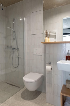 A bathroom with a glass-enclosed shower, a white toilet, a sink, and a mirror above the sink. - Tribera Vienna Erdberg (Vienna)