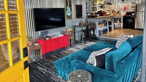 Ein modernes Wohnzimmer mit einem großen Flachbildfernseher, einem roten Schrank und einem türkisfarbenen Sofa.