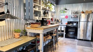 Eine Küche mit Kochinsel, Barhocker, Kühlschrank und verschiedenen Küchengeräten.